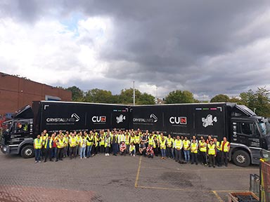 People in hi-vis jackets near two lorries with the slogan Crystal Units on the side.