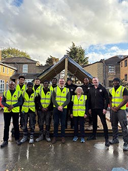 A group of people in hi-vis jackets outside: ground is wet.