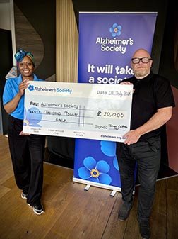 Two people holding a large cheque made out to the Alzheimer's Society.