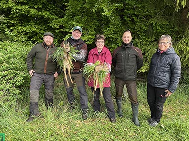 Five people with two fawns in a woodland setting.