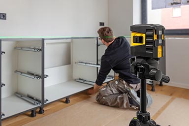 A kitchen fitter using the laser to assist with the installation of cabinets.