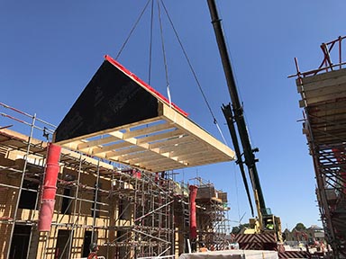 A roof being lowered into place in a timber frame building.