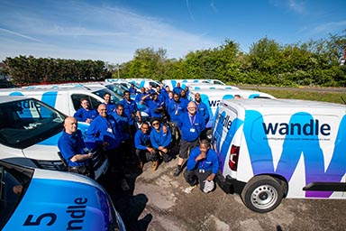 Several vans with the Wandle logo with several men wearing with blue tops, presumably the van drivers.
