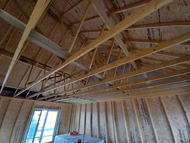 A house under construction, looking upwards from the inside towards the roof and rafters.